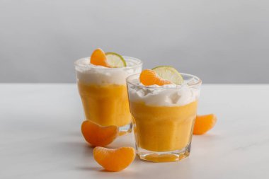 two glasses with cream desserts with tangerine and lime slices clipart