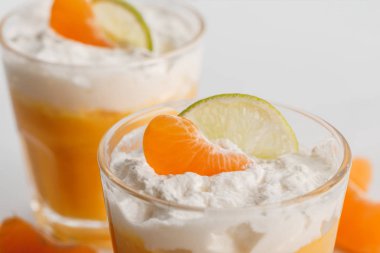 close up of two glasses of cream desserts with tangerine and lime slices clipart