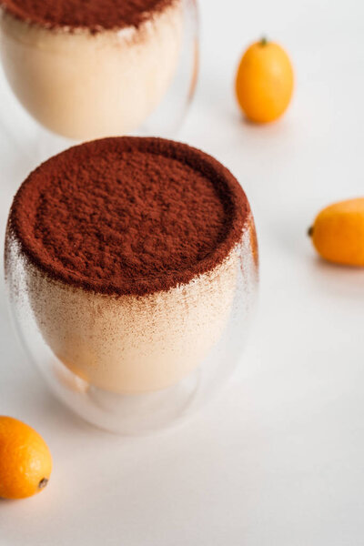 tiramisu desserts with cocoa powder and kumquats in two glasses