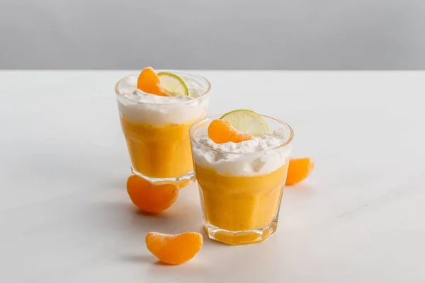 タンジェリンとライムのスライスとオレンジ色のデザート グラス — ストック写真