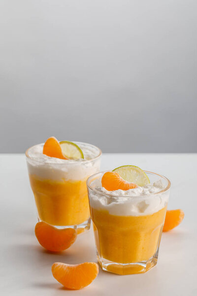 two glasses with orange mousse with tangerine and lime slices