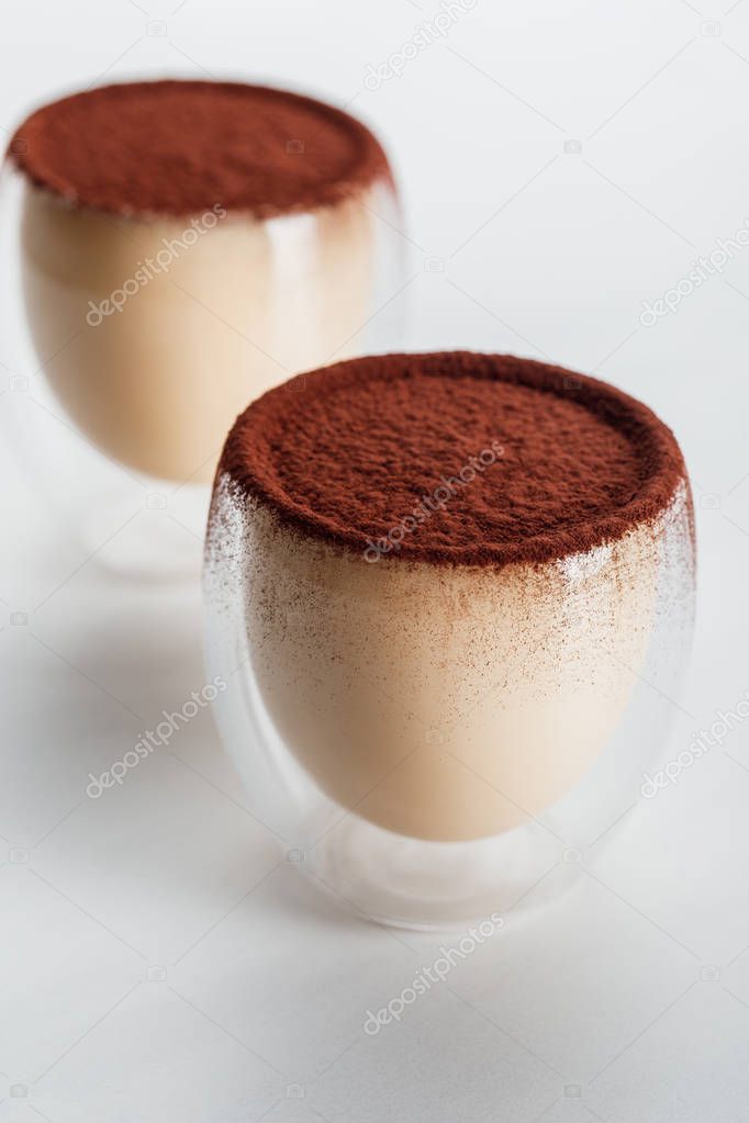 sweet tiramisu desserts with cocoa powder in two glasses