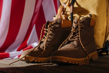 close-up view of trekking boots, backpack and american flag on wooden surface, travel concept  clipart