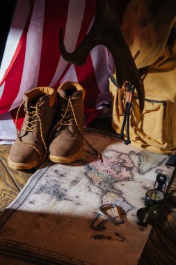 çizme, harita, pusula, sırt çantası ve Amerikan bayrağı ahşap yüzeyde trekking