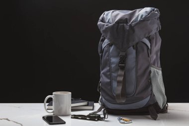 backpack, smartphone, cup, notebooks and compass on black, travel concept  clipart