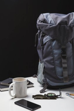 backpack, smartphone, cup and compass on black, travel concept  clipart