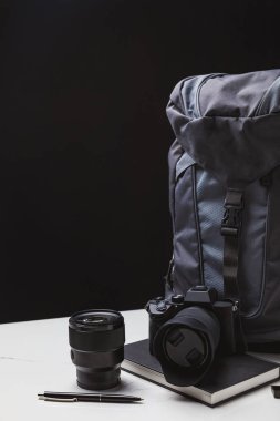 sırt çantası, fotoğraf makinesi lens ile ve defter kalem siyah ile 