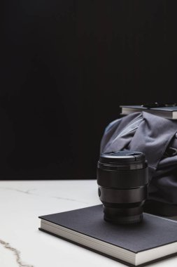 close-up view of photo lens on notebook and backpack on black clipart