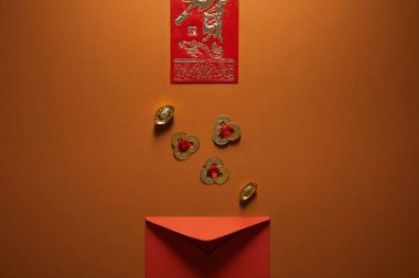 top view of red envelope, golden chinese decorations and hieroglyph on brown background clipart