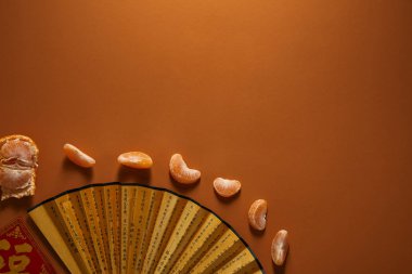 hiyeroglif ve soyulmuş mandalina ile altın fan üstten görünüm kahverengi zemin üzerine