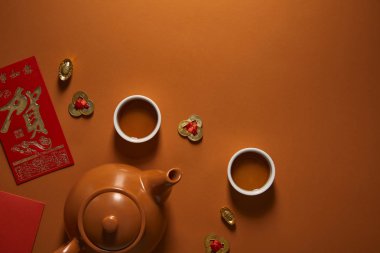 top view of tea set and traditional chinese decorations on brown background clipart