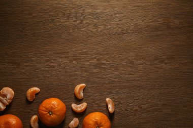 top view of whole and peeled tangerines on wooden background clipart
