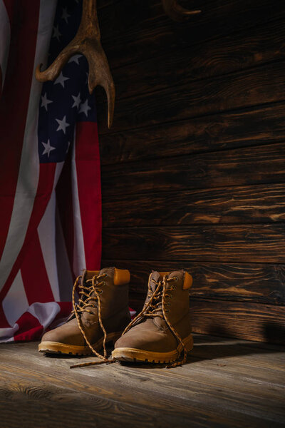 trekking boots, horns and american flag on wooden surface, travel concept 