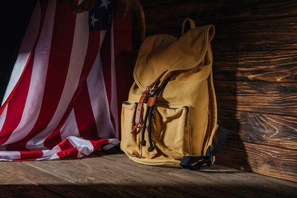 backpack and american flag on wooden surface, travel concept 