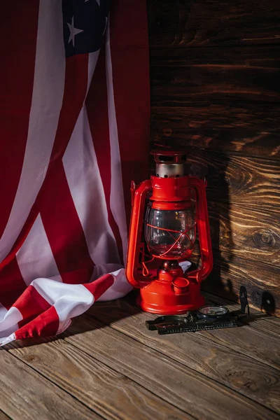 close-up view view of american flag, red lantern and compass on wooden surface