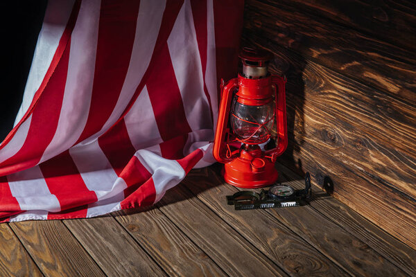 american flag, red lantern and compass on wooden surface 