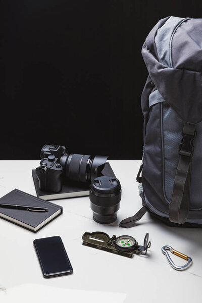 backpack, smartphone, photo camera with lens and tracking equipment