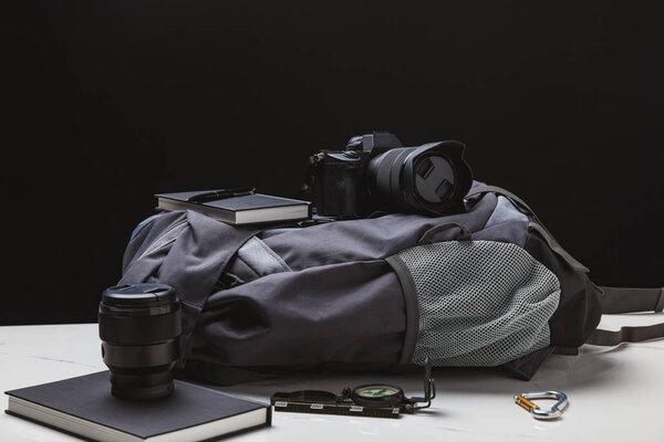 backpack, photo camera and trekking equipment on black