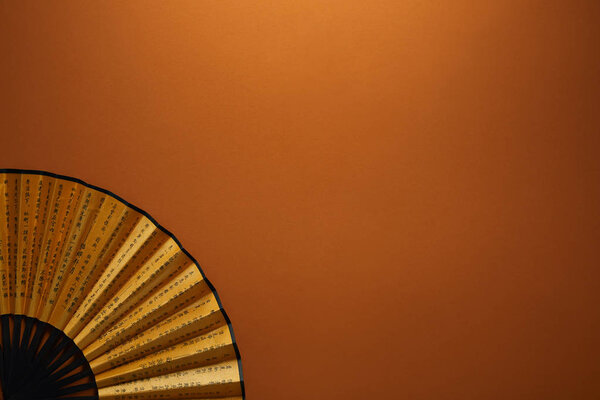 close-up view of decorative black and golden fan with hieroglyphs on brown background