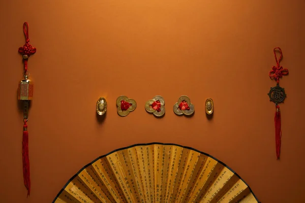 traditional golden chinese decorations and fan with hieroglyphs on brown background