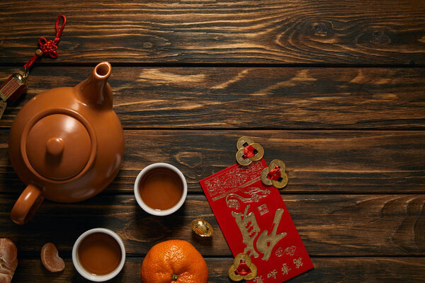 top view of tea set and traditional decorations on wooden table, chinese new year composition