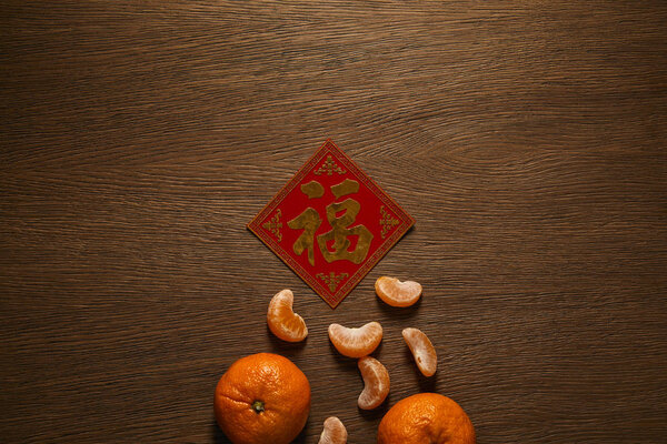 top view of fresh ripe tangerines and golden hieroglyph on wooden table