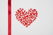 heart shaped arrangement of small red paper cut hearts with satin ribbon on white background
