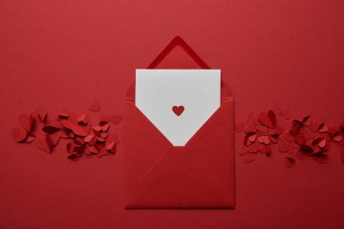 üstten görünüm Kağıt zarf içinde beyaz mektubunun kalpler kırmızı zemin üzerine kesilmiş.