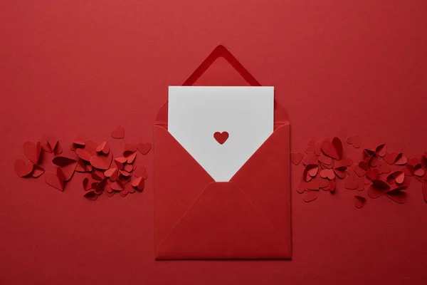 在红色背景上用剪纸心的信封中的白色字母的顶部视图 — 图库照片