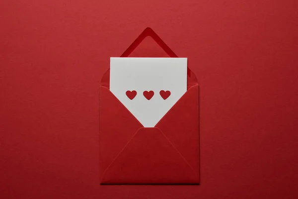 白色信件的顶部看法与心脏在信封在红色背景 — 图库照片