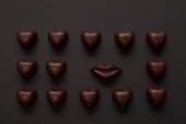Draufsicht auf leckere Schokoladenlippen und Schokoladenherzen auf schwarzem Hintergrund 
