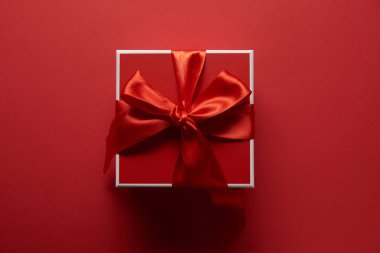 top view of present with silk ribbon on red background clipart