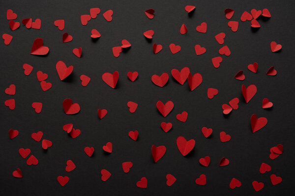seamless black background with copy space and paper cut red hearts 