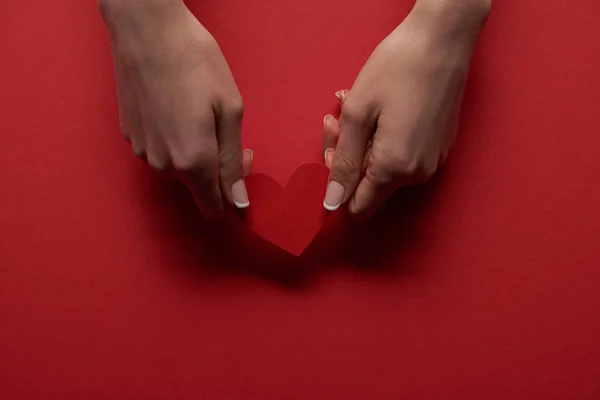 女性手拿着心脏卡片的部份看法在红色背景 — 图库照片