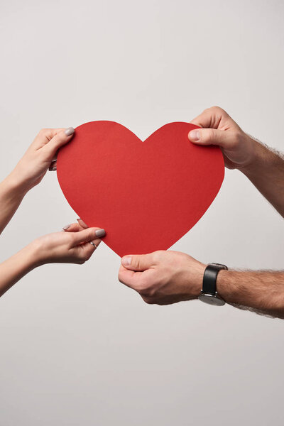 cropped view of couple holding together blank heart card isolated on grey