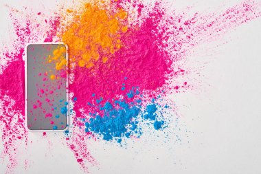 Beyaz arka plan üzerinde smartphone ve patlama çok renkli holi tozu üstten görünüm