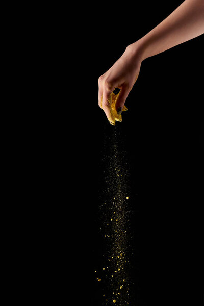 cropped view of adult woman holding and sprinkling yellow holi powder on black background