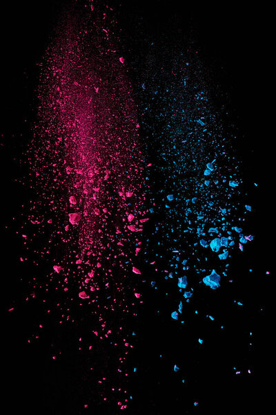  pink and blue holi powder in air on black background