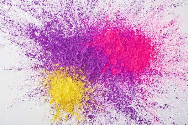 top view of explosion of purple, pink and yellow holi powder on white background