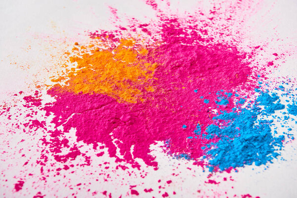 top view of explosion of multicolored holi powder on white background