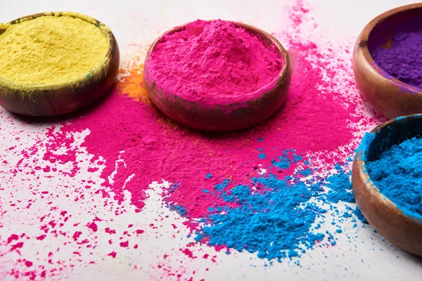 Beyaz arka plan üzerinde renkli holi tozu ile ahşap kase