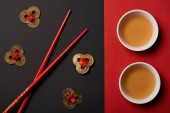 pohled shora na hůlky s tradiční čínské čaje a feng shui mince na červené a černé pozadí