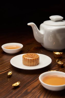traditional mooncake with tea cups, pot and gold ingots isolated on black clipart