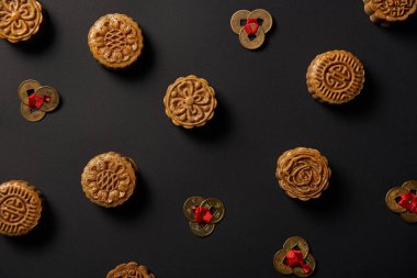 top view of traditional mooncakes and feng shui coins isolated on black clipart