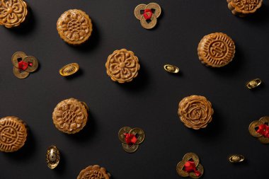 top view of traditional mooncakes and feng shui coins isolated on black clipart