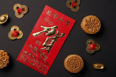 top view of traditional mooncakes with chinese hieroglyphs and feng shui coins isolated on black clipart