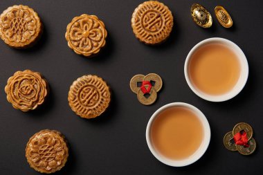 geleneksel mooncakes, çay bardak ve feng shui sikke üzerinde siyah izole üstten görünüm