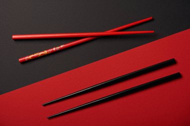 top view of two sets of chopsticks on red and black background clipart