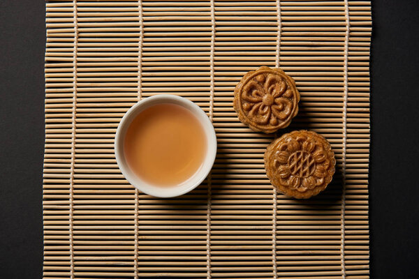 top view of chinese mooncakes and tea cup on bamboo table mat