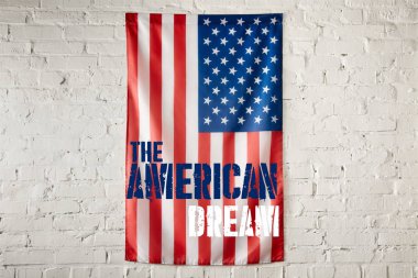close up view of united states of america flag with the american dream lettering on white brick wall  clipart